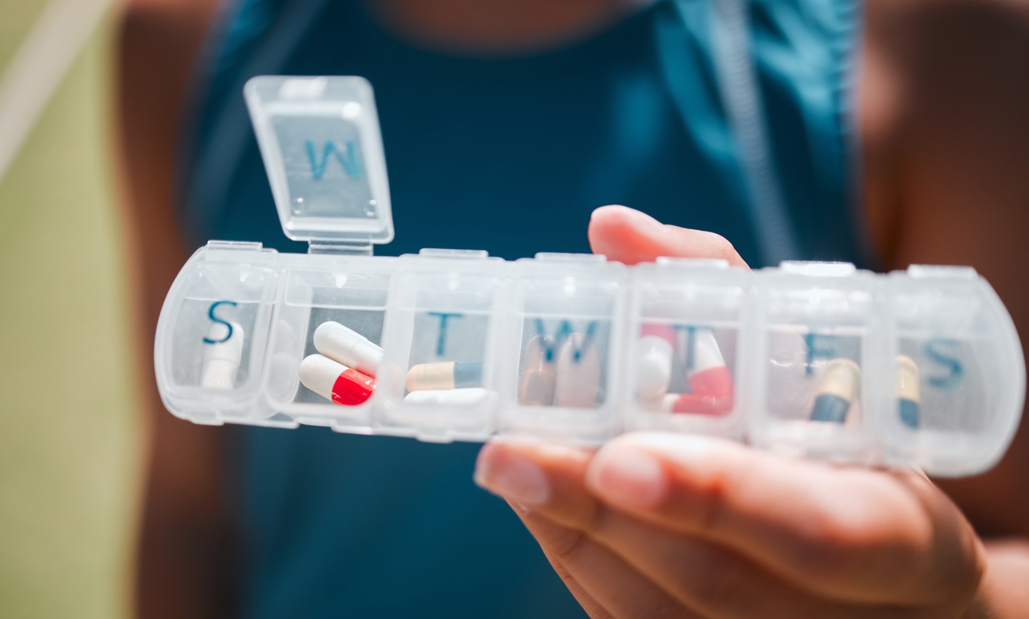 Hands, medicine and pills container schedule for health, wellness and medication reminder for vital